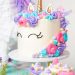 Finished unicorn cake with colorful frosting decorations, a golden horn, and eyes drawn on the icing.