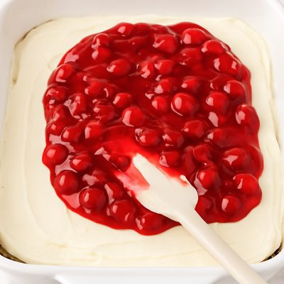 Adding the cherry pie filling evenly across the top No-Bake Chocolate Cherry Lush: Layered Dessert Recipe