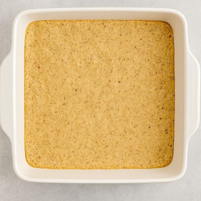 Pressing the crust into a 9x13 dish and baking it No-Bake Chocolate Cherry Lush: Layered Dessert Recipe