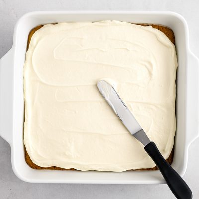 Spreading the cream cheese Cool Whip and powdered sugar mixture No-Bake Chocolate Cherry Lush: Layered Dessert Recipe