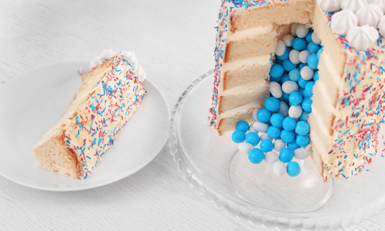 gender-reveal-cakeA slice of cake on a plate next to a layered reveal cake spilling blue candies, highlighting the excitement of the moment.