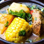 A close-up shot of a Caldo de Res recipe bowl featuring tender beef, corn, and vegetables, topped with fresh cilantro, highlighting the soup’s warm and comforting texture