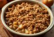 Warm and comforting homemade apple crisp topped with a buttery oat crumble, served fresh from the oven and garnished with a scoop of vanilla ice cream, perfect for a cozy dessert.