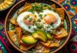 Celebrating Chilaquiles A colorful bowl of green chilaquiles topped with two sunny-side-up fried eggs, sliced avocado, crumbled queso fresco, and fresh cilantro, served on a traditional Mexican patterned tablecloth