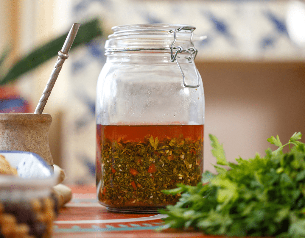 Chimichurri Sauce: Learn How to Make the Authentic Chimichurri Sauce Recipe from Argentina 11 Close-up of freshly made chimichurri sauce in a glass jar, showcasing its vibrant green color and texture.