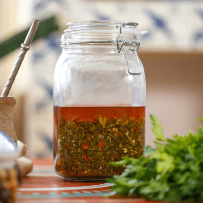 Close-up of freshly made chimichurri sauce in a glass jar, showcasing its vibrant green color and texture.