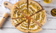 Pickle Pie Pizza Sliced dill pickle pizza on a wooden board with a golden crust and creamy garlic drizzle.