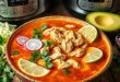 A rustic bowl of pozole soup (also called pazole), filled with hominy and shredded meat, served with vibrant toppings like radishes, lime wedges, and tortillas—perfect for a hearty chicken pozole feast.