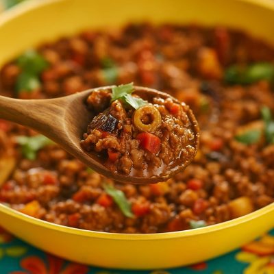 Traditional Puerto Rican picadillo served in a skillet, featuring seasoned ground beef, green olives, and sofrito, garnished with fresh herbs
