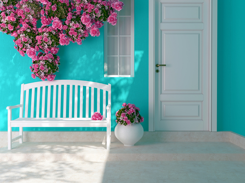 Entrance of a house. Front view of a wooden white door on a blue house with window. Beautiful roses and bench on the porch. Entrance of a house.