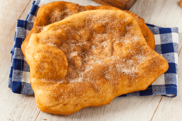 Golden, freshly fried dough sprinkled with powdered sugar, perfect for recreating a classic fairground dessert at home.