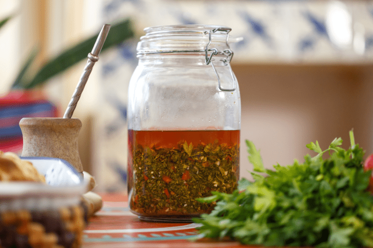 Close-up of freshly made chimichurri sauce in a glass jar, showcasing its vibrant green color and texture.