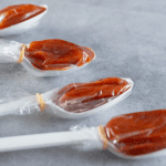 Close-up shot of plastic spoons each filled with soft, tangy tamarind candy wrapped in cellophane. These individually portioned spoons capture the sweet-and-sour flavor prized in many Mexican candies
