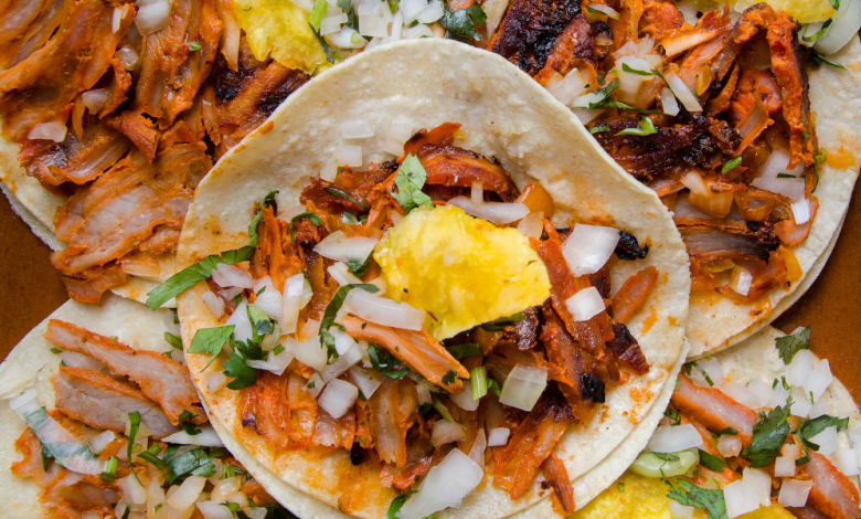 Close-up of tacos al pastor with juicy marinated pork, fresh cilantro, and a slice of pineapple.