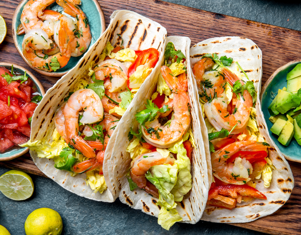 Easy Shrimp Ceviche Recipe: The Best Ceviche You Can Cook at Home 11 A closer look at shrimp cradled in soft tortillas and topped with chopped lettuce, peppers, and herbs. The accompanying bowls of pico de gallo and diced avocado invite you to customize each bite.